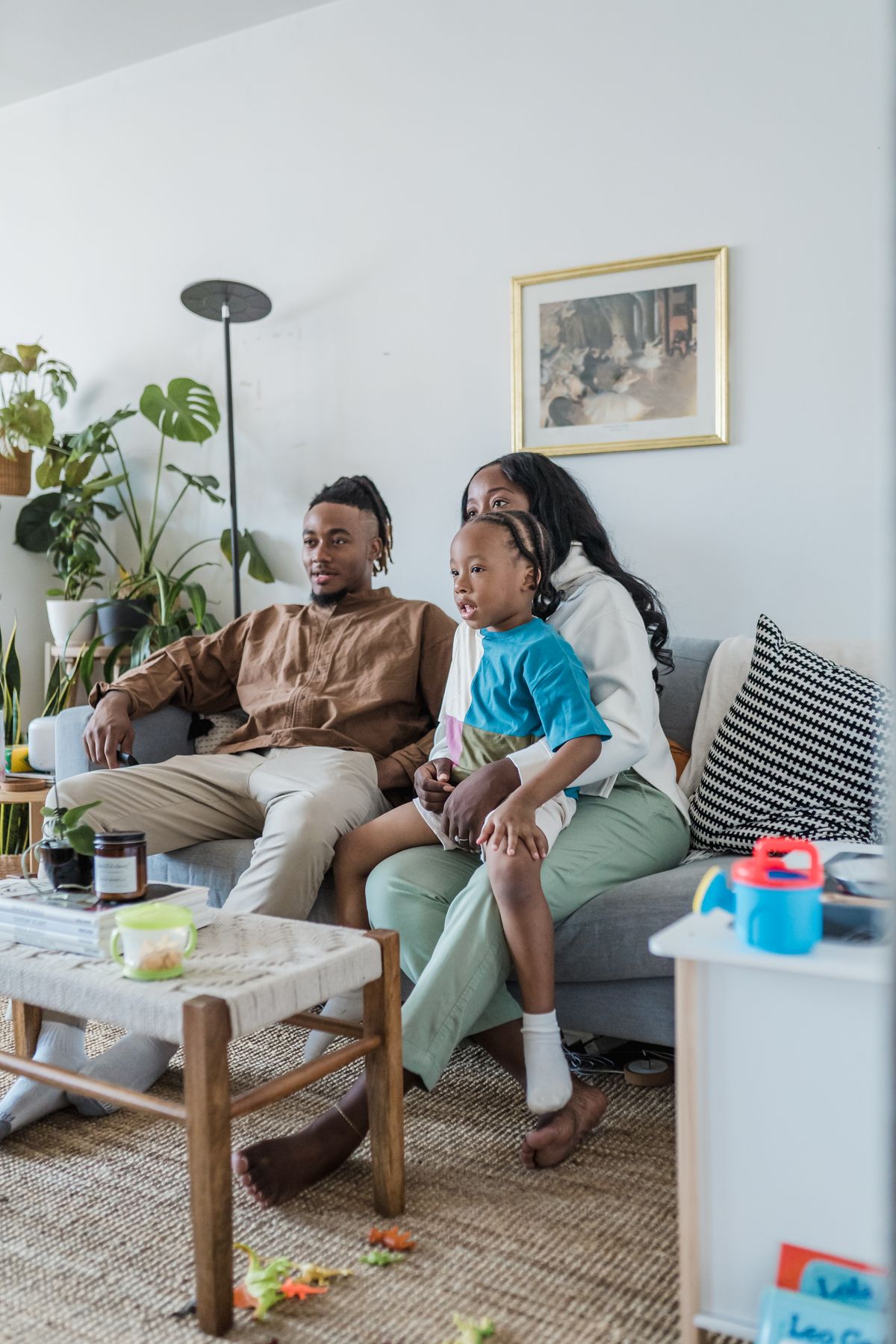 Parents and a young child watching a cartoon on television in their living room